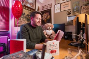 Dr Jim Everett reads a Valentine's card written by AI at a desk surrounded by Valentine's-themed gifts