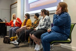 A panel of speakers listening to a member of the panel in a lecture theatre
